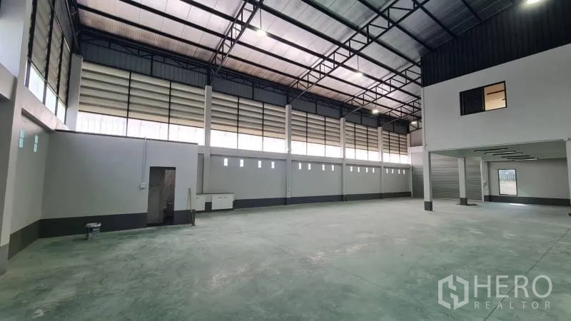 Warehouse for rent in Bang Bua Thong, Nonthaburi - Spacious warehouse interior with high steel truss roof, polished concrete floor, and louvered side windows.