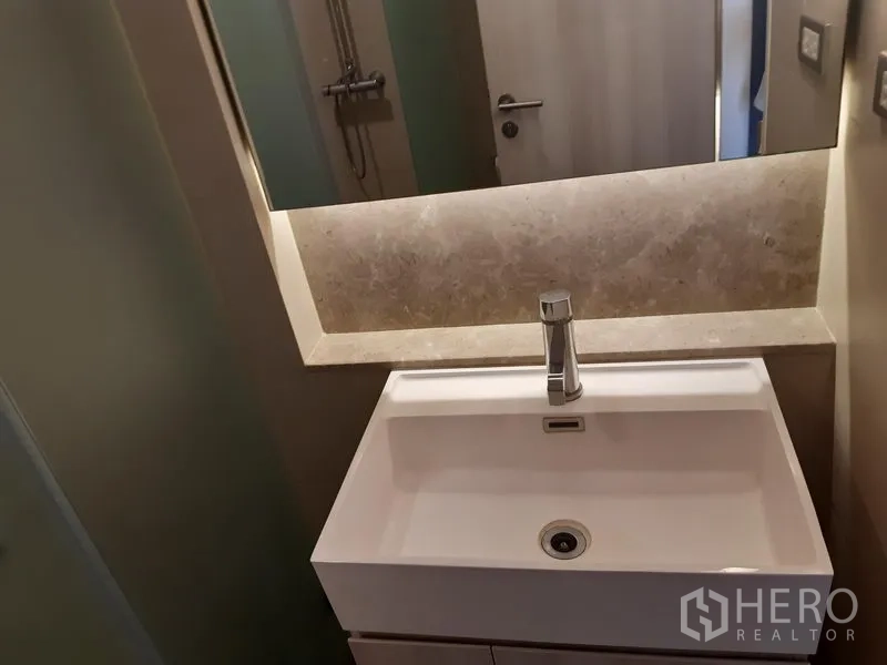 Condominium for rent in Khlong Toei, Bangkok - Modern shower bathroom with rectangular basin and backlit mirror.