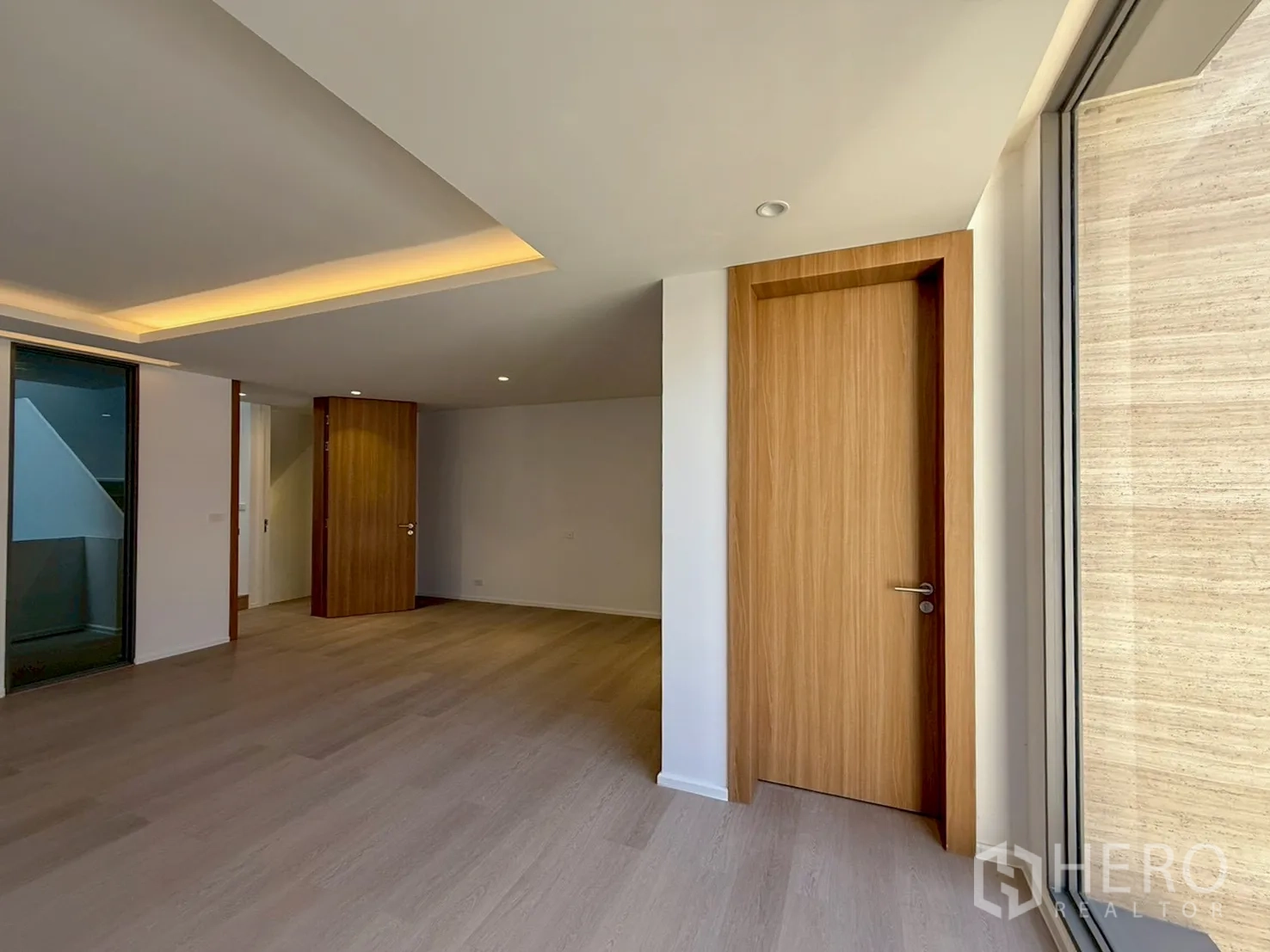 家庭办公室 for rent or sale in Watthana, Bangkok - 明亮房间，木质门、嵌入式灯光与宽窗。