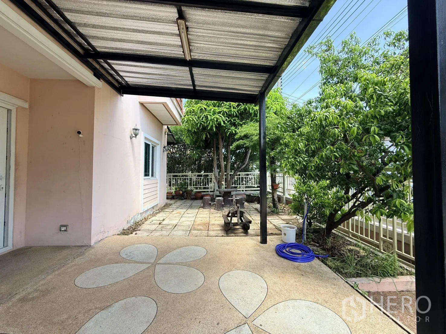 Detached House for rent in Lam Luk Ka, Pathum Thani - Covered patio beside the house with paved area and greenery.
