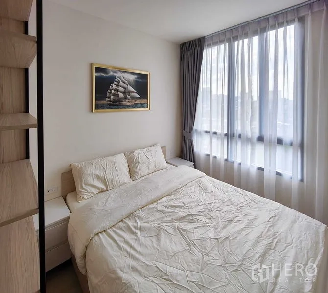 Condominium for rent - Bright master bedroom with large curtained window and framed ship painting above the bed.