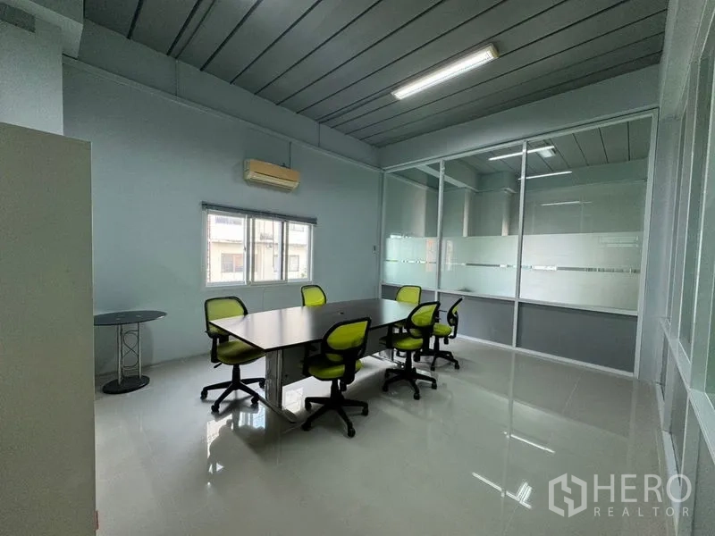 Warehouse for rent or sale in Chon Buri - Meeting room with long table and green chairs inside a glass-walled office.