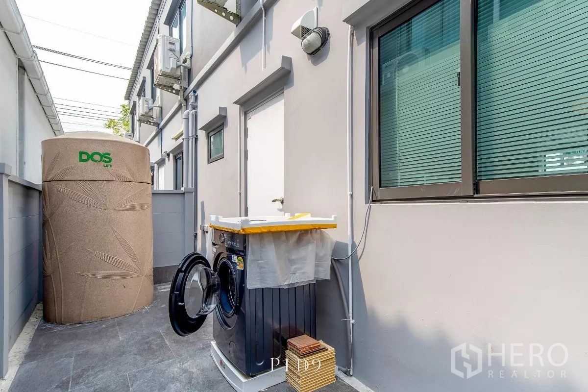 Townhouse for rent in Bang Phli, Samut Prakan - Side yard utility zone with washing machine and large water tank