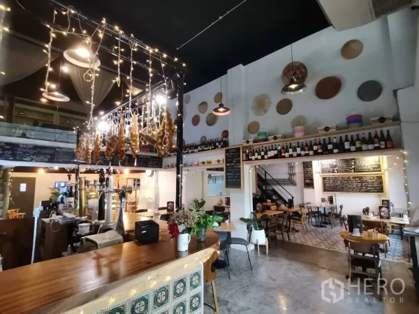 零售空间 出租在Watthana, Bangkok - 室内木质吧台，吊灯与酒瓶陈列，氛围温暖。