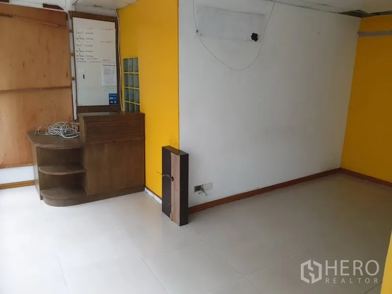 พื้นที่ขายปลีก ให้เช่าในWatthana, Bangkok - ห้องมุมขนาดเล็ก ผนังสีขาว–เหลือง พื้นกระเบื้อง พร้อมเคาน์เตอร์ไม้บิลท์อิน