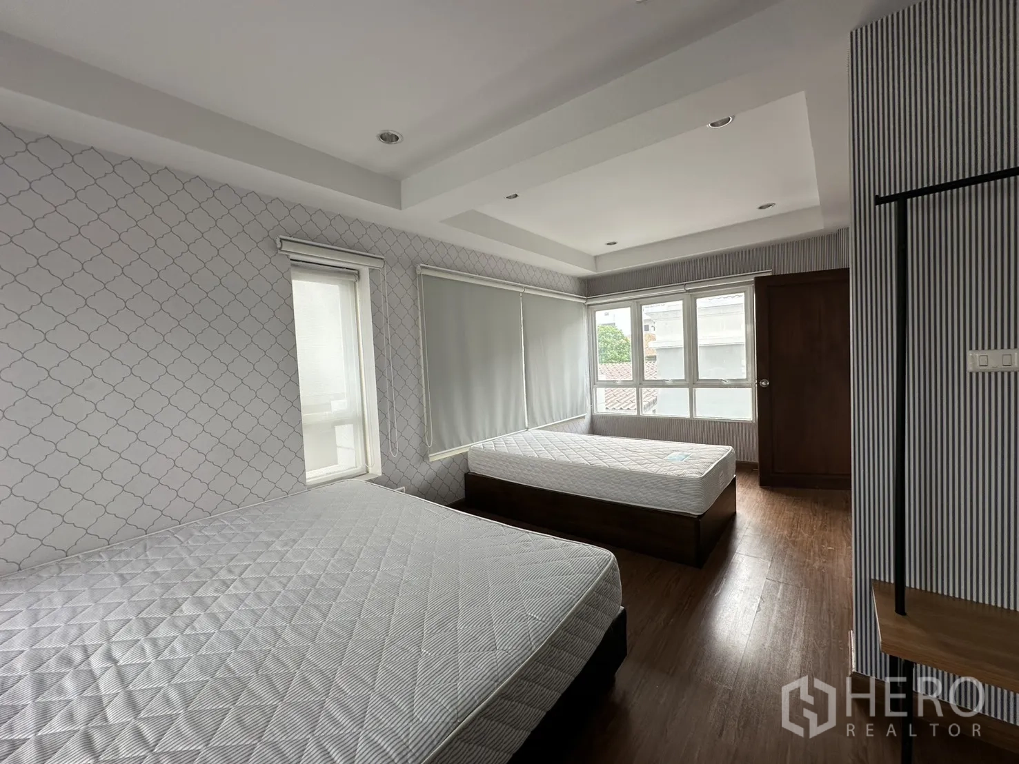 Home Office for rent in Watthana, Bangkok - Bedroom with two beds, patterned wallpaper, recessed ceiling lights and windows.