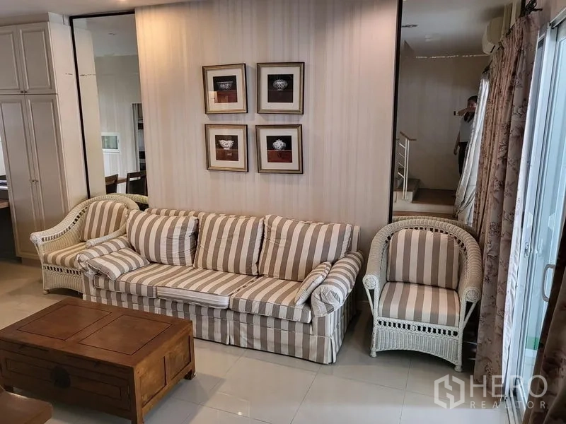 Townhouse for rent in Wang Thonglang, Bangkok - Cozy lounge with striped sofa set, wooden coffee table and framed art.