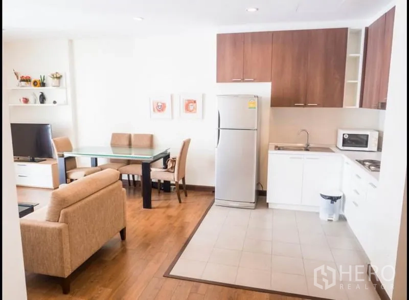 公寓 出租或出售在Phra Khanong, Bangkok - 开放式厨房，上柜与冰箱相连，旁为餐桌与起居区。