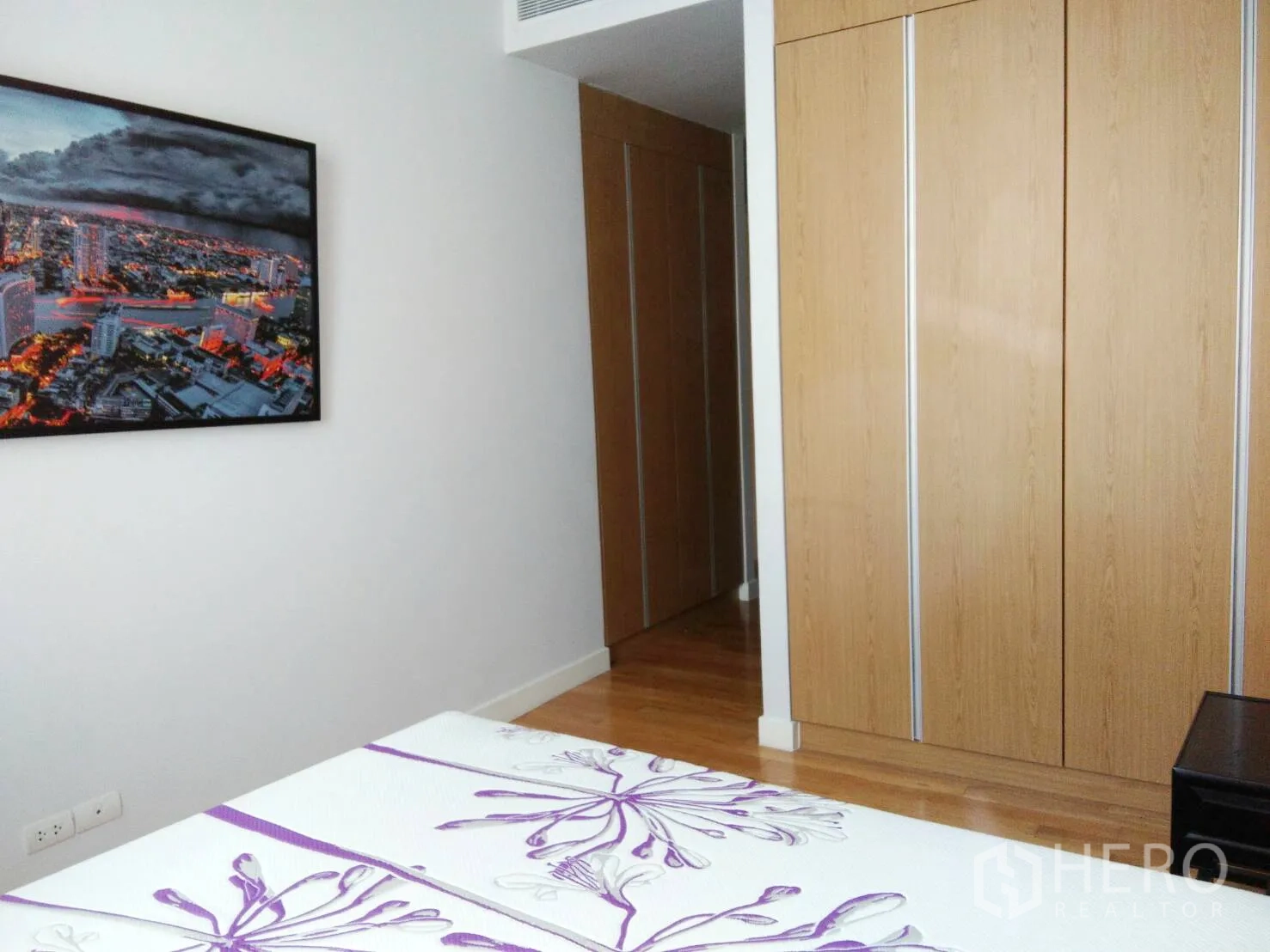 คอนโด ให้เช่าในKhlong Toei, Bangkok - ห้องนอนพร้อมตู้เสื้อผ้าบิวท์อินลายไม้และภาพเมืองแขวนผนัง