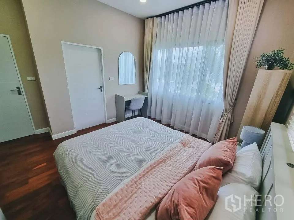 Detached House for rent or sale in Bang Phli, Samut Prakan - Bedroom with tall curtains, work desk, and soft pink bedding.