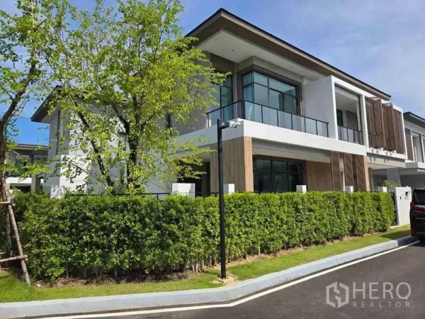 บ้าน ให้เช่าในBang Phli, Samut Prakan - มุมมองภายนอกบ้านเดี่ยวสมัยใหม่ ระเบียงกระจกและแนวรั้วต้นไม้