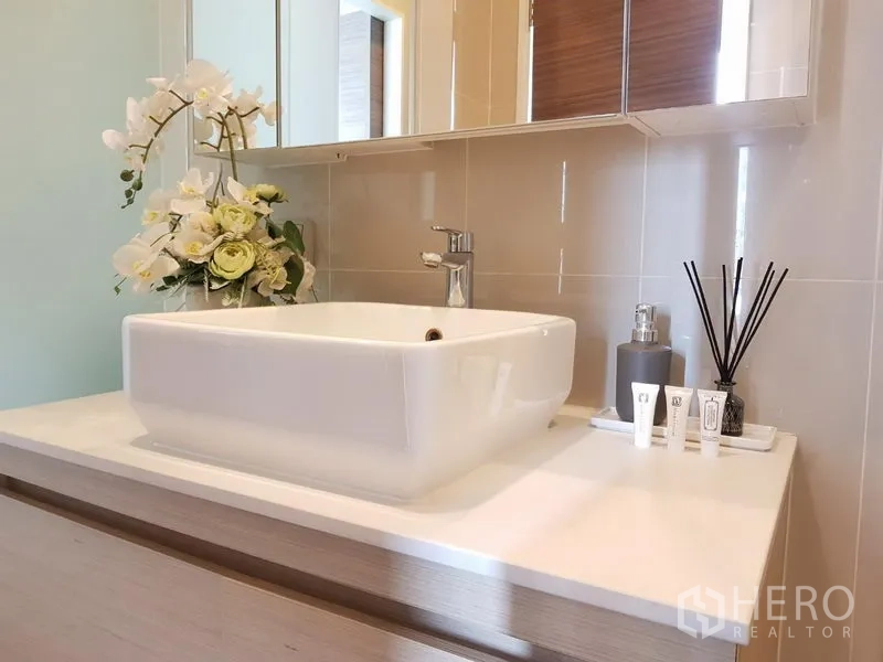 公寓 出租在Ratchathewi, Bangkok - 当代风格卫浴台，方形面盆、镜柜与香薰摆件。