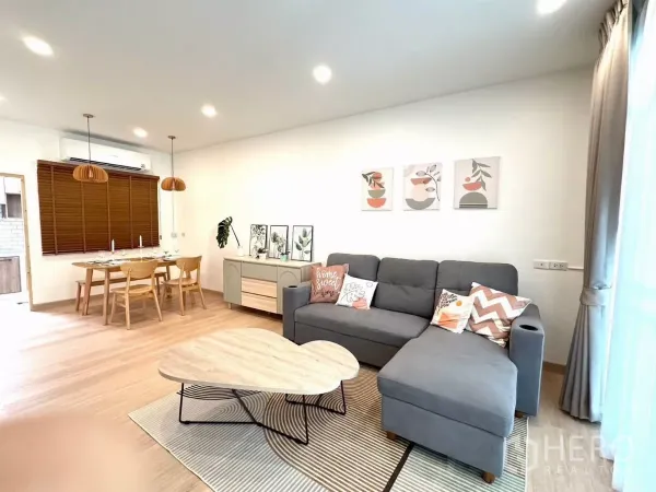 ทาวน์เฮาส์ ให้เช่าในBang Phli, Samut Prakan - พื้นที่นั่งเล่นและทานอาหารแบบโอเพ่นพลาน โซฟา L สีเทา และงานไม้โทนอุ่น