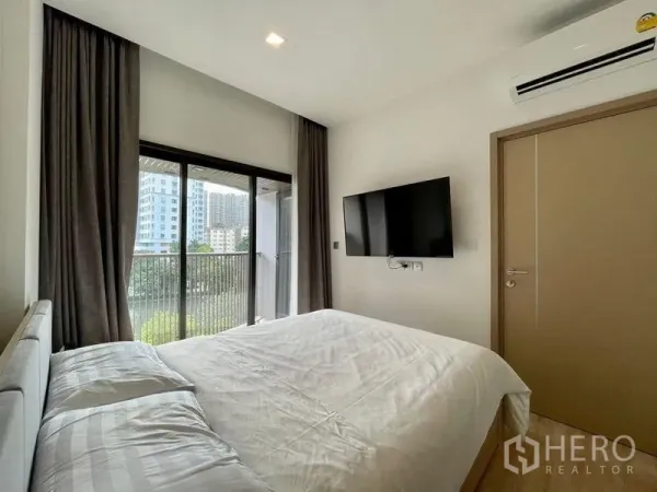 คอนโด ให้เช่าหรือขายในWatthana, Bangkok - ห้องนอนโปร่งติดแอร์ ทีวีติดผนัง และประตูเลื่อนออกระเบียงเห็นวิวเมืองและต้นไม้