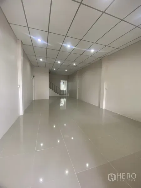 ทาวน์เฮาส์ ให้เช่าในSuan Luang, Bangkok - โถงชั้นล่างแบบโอเพ่นสเปซ พื้นกระเบื้องเงา ไฟดาวน์ไลท์ และบันไดอยู่ด้านหลัง