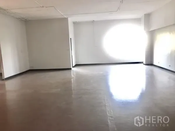 Office Space for rent in Watthana, Bangkok - Sunlit open-plan workspace with a large window and higher ceiling.