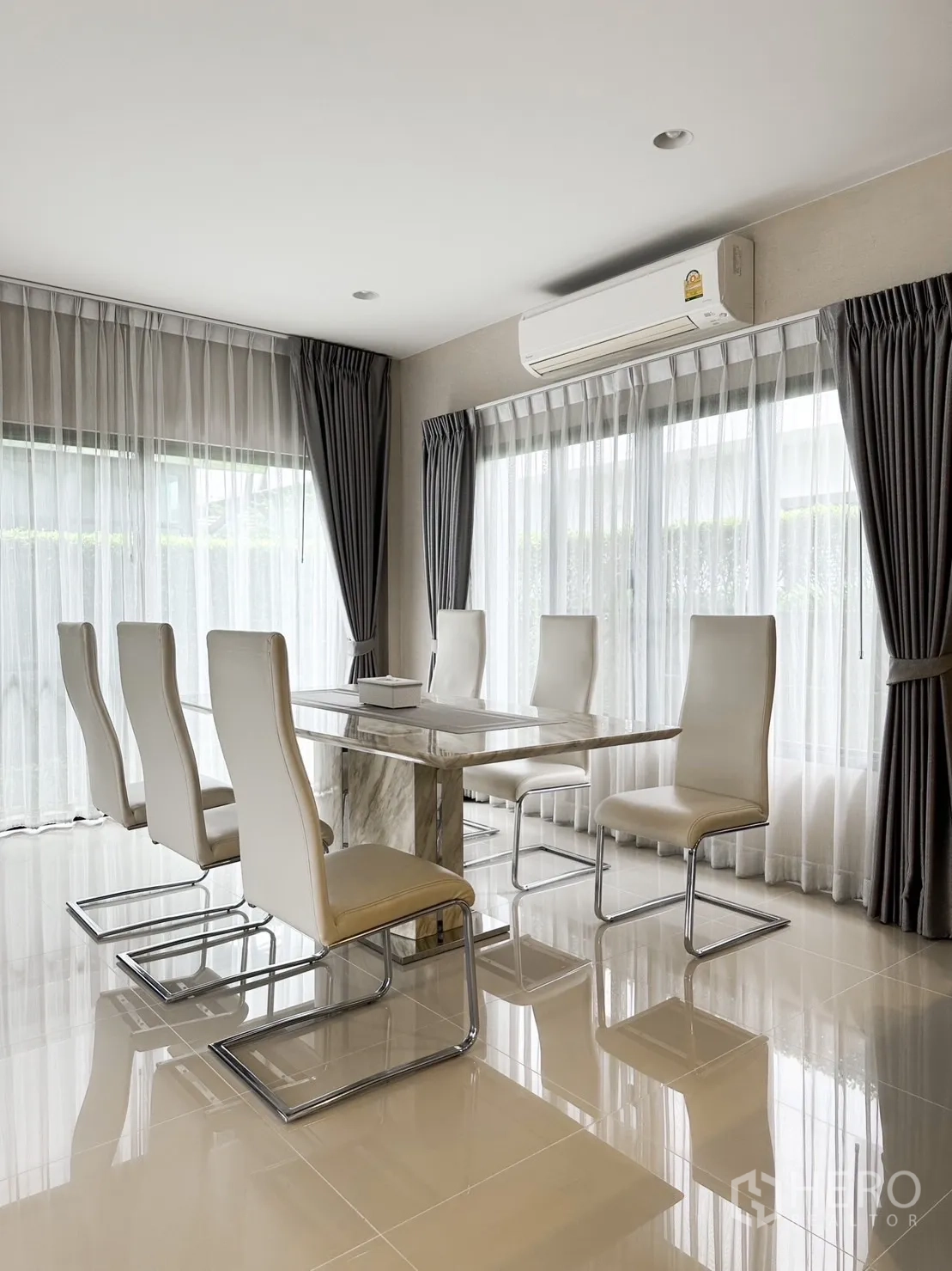 Detached House for rent or sale in Bang Kapi, Bangkok - Dining room with marble table, six white chairs and wraparound windows.