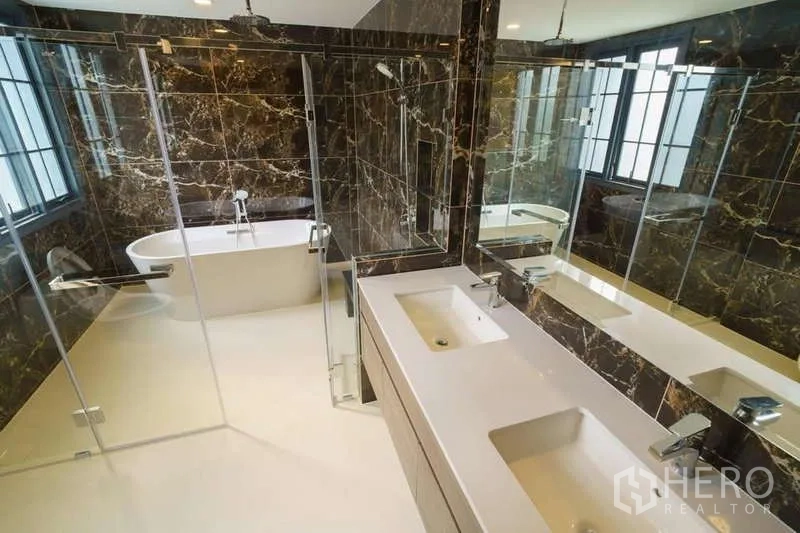 Detached House for rent or sale in Bang Phli, Samut Prakan - Luxury bathroom with double vanity, glass shower and freestanding bathtub with marble walls.