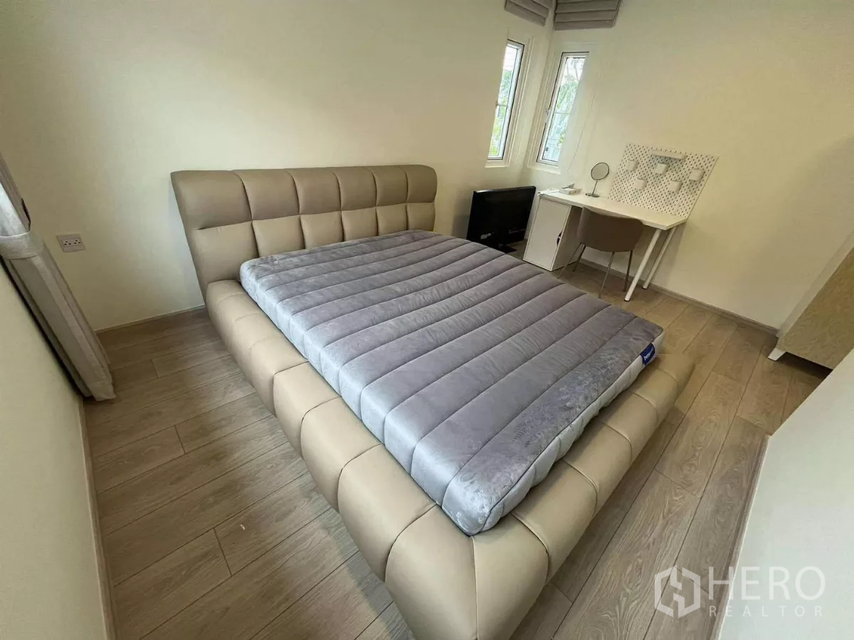 Detached House for rent in Bang Phli, Samut Prakan - Cozy bedroom with padded bedframe, wood floors, and study desk by windows.