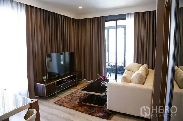 คอนโด ให้เช่าในHuai Khwang, Bangkok - ห้องนั่งเล่นสว่างในคอนโด พร้อมโซฟาสีครีม ชุดทีวี และประตูกระจกออกระเบียง