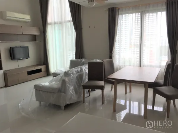 Condominium for rent in Ratchathewi, Bangkok - Bright Bangkok Ratchathewi condo living and dining area with floor-to-ceiling windows, TV console and city view.