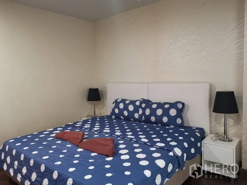 คอนโด ให้เช่าหรือขายในWatthana, Bangkok - ห้องนอนหลักพร้อมเตียงคิง ผ้าปูจุดลายโพลก้า โต๊ะข้างเตียงและโคมไฟ