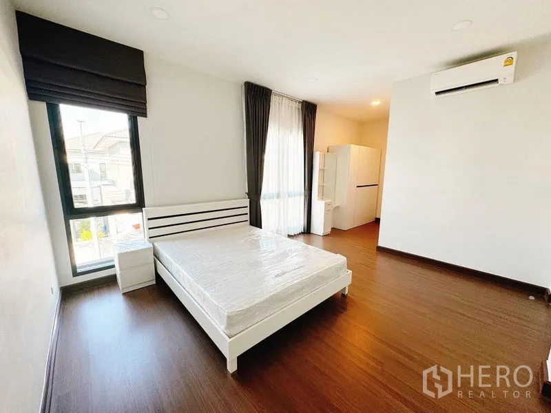 Detached House for rent in Bang Phli, Samut Prakan - Bright bedroom with double bed, wood flooring, floor-to-ceiling windows and air conditioning.