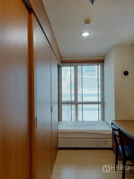 Condominium for rent in Bang Rak, Bangkok - Small bedroom with single bed, floor-to-ceiling wardrobes and window blinds.