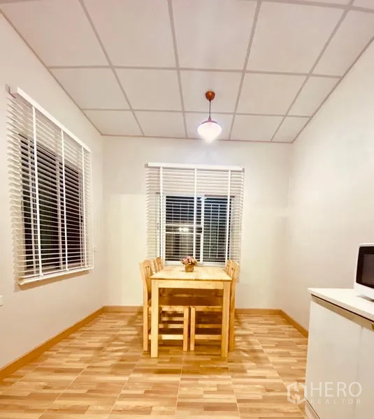 联排别墅 出租在Prawet, Bangkok - 用餐角，木质餐桌套装，旁有两扇配百叶的窗。