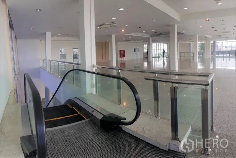 Retail Space for rent in Prawet, Bangkok - Escalator entry connecting levels inside a large open showroom with downlights.