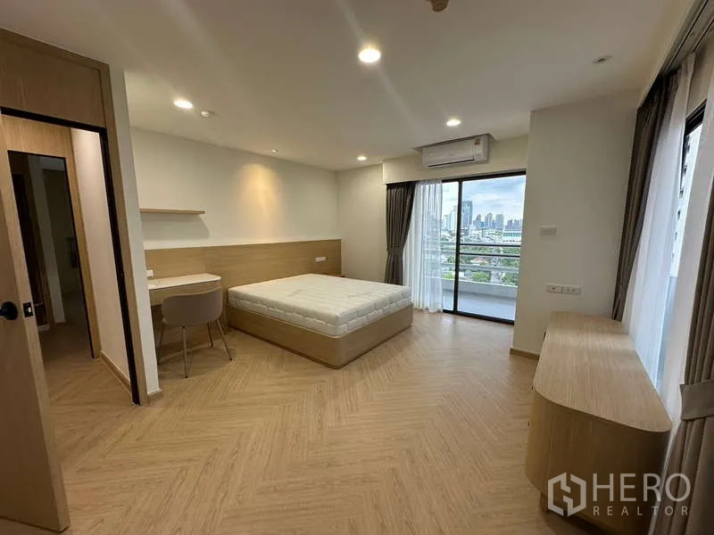 คอนโด ให้เช่าในWatthana, Bangkok - ห้องนอนขนาดใหญ่พร้อมโต๊ะทำงาน ตู้วางของ และประตูกระจกสู่ระเบียงวิวเมือง