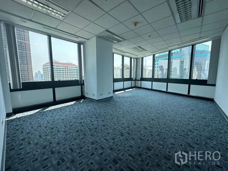 Office Space for rent in Khlong Toei, Bangkok - Corner office with carpet tiles and wraparound windows offering city views.