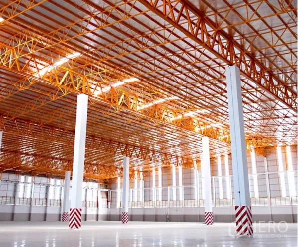 Warehouse for rent in Chachoengsao - Spacious warehouse interior featuring high ceiling, orange steel trusses and polished floor.