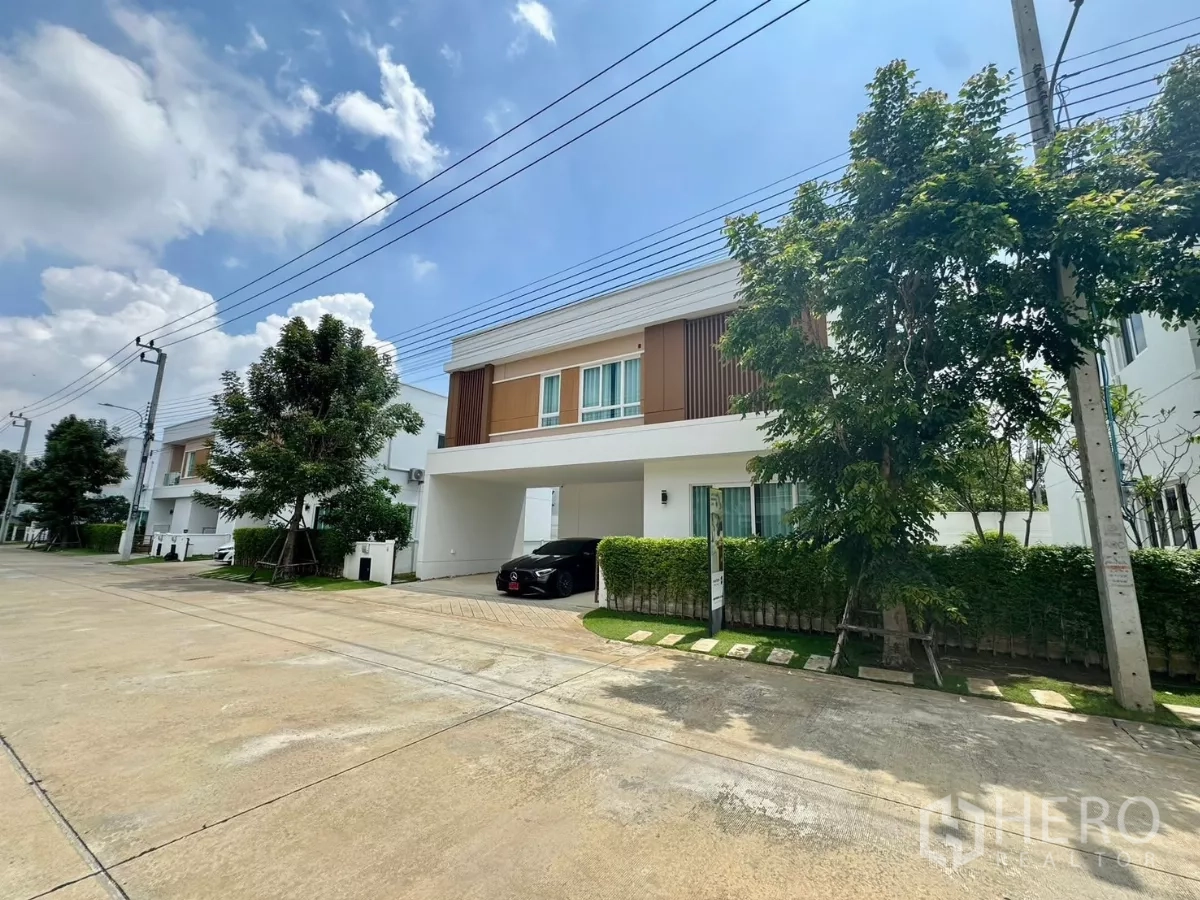 Detached House for rent or sale in Bang Bo, Samut Prakan - Tree-lined residential street with contemporary detached houses and wide driveway.