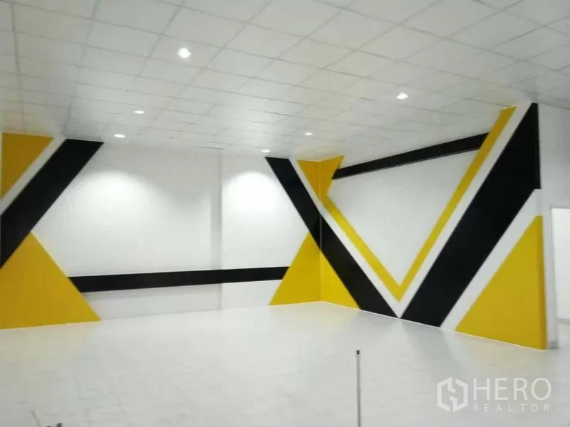 Home Office for rent or sale in Pak Kret, Nonthaburi - Spacious multipurpose room with white tile floor and bold yellow and black geometric wall.