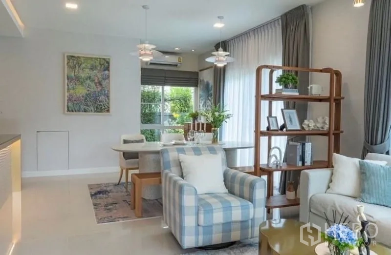 Detached House for rent in Bang Phli, Samut Prakan - Cozy lounge with checkered armchair, open shelving and dining area beyond.