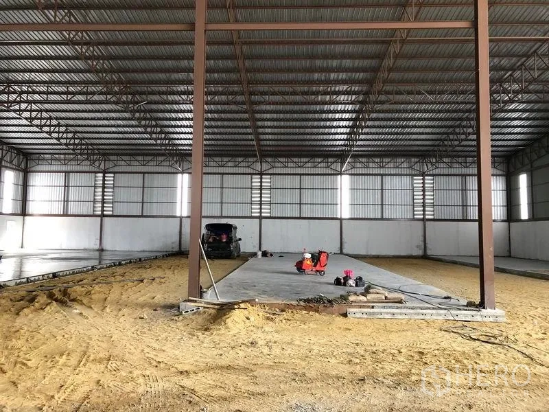 Warehouse for rent or sale in Sai Noi, Nonthaburi - Central concrete strip slab between steel columns inside an expansive warehouse.