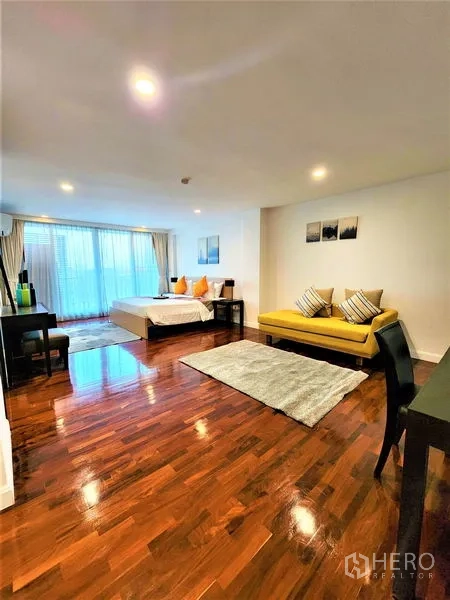 公寓 出租在Bang Rak, Bangkok - 超大卧室套间，黄色沙发、书桌与阳台门。