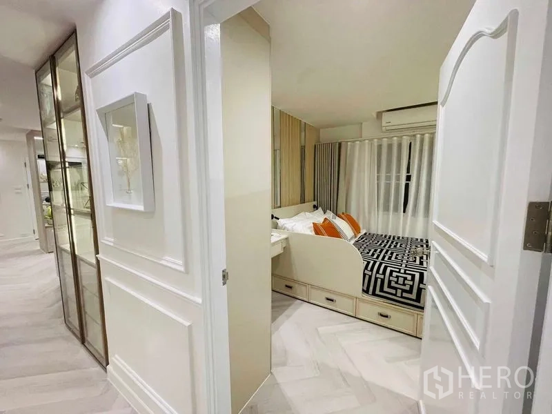 Condominium for sale in Yan Nawa, Bangkok - Hallway view into bedroom with under-bed storage drawers and glass display cabinet.