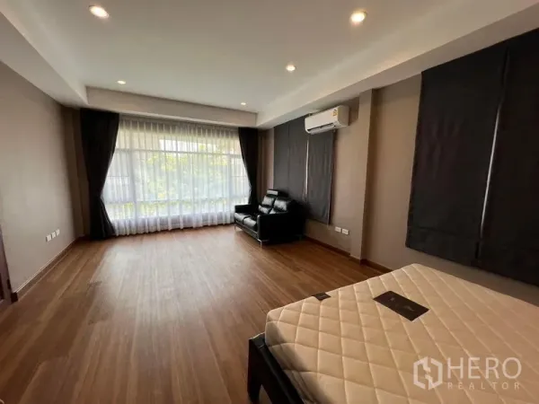 Detached House for sale in Mueang Pathum Thani, Pathum Thani - Spacious bedroom with wood flooring, full-height window, air conditioner and lounge chair