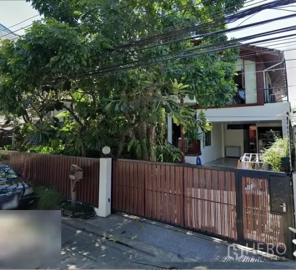 บ้าน ขายในSuan Luang, Bangkok - ประตูรั้วไม้พร้อมที่จอดรถในร่มและต้นไม้ใหญ่หน้าโครงการ