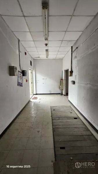 Retail Space for rent in Phra Khanong, Bangkok - Long interior room with tiled floor, drop ceiling and fluorescent lights, showing a side door.