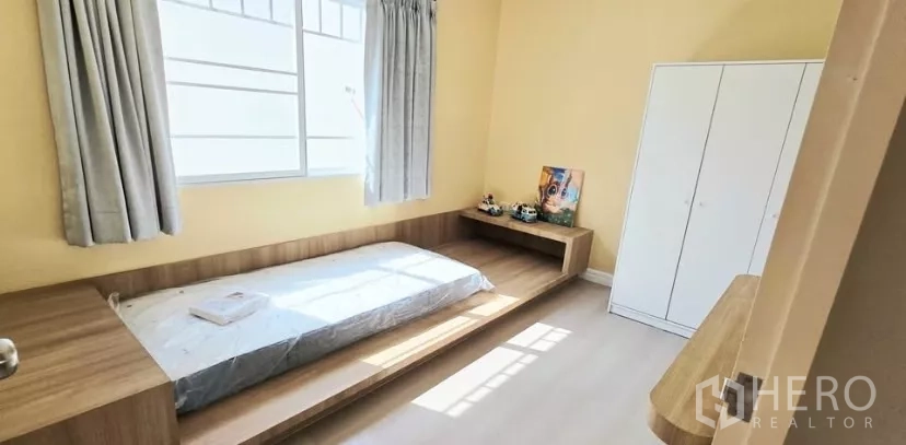 Townhouse for rent in Bang Bo, Samut Prakan - Cozy bedroom with platform bed, large window and wardrobe.