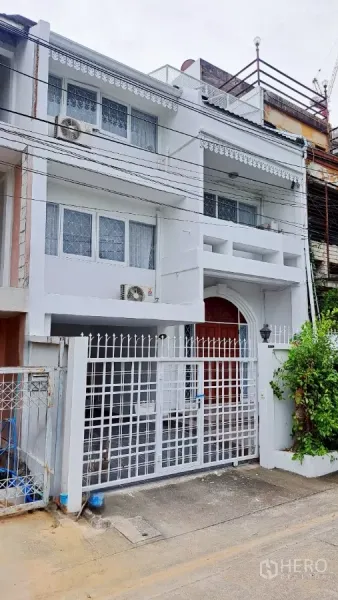Townhouse for rent in Watthana, Bangkok - Three-storey white townhouse exterior with gated entrance and balconies in Watthana.