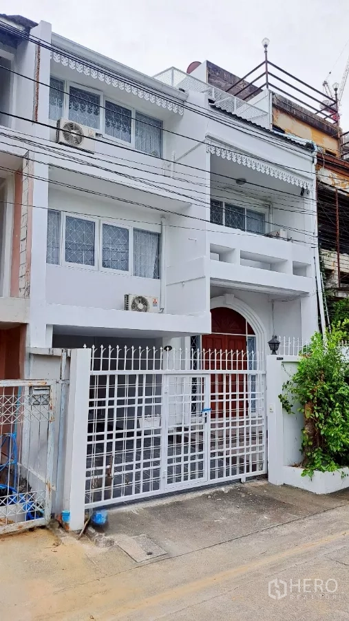 Townhouse for rent in Watthana, Bangkok - Three-storey white townhouse exterior with gated entrance and balconies in Watthana.