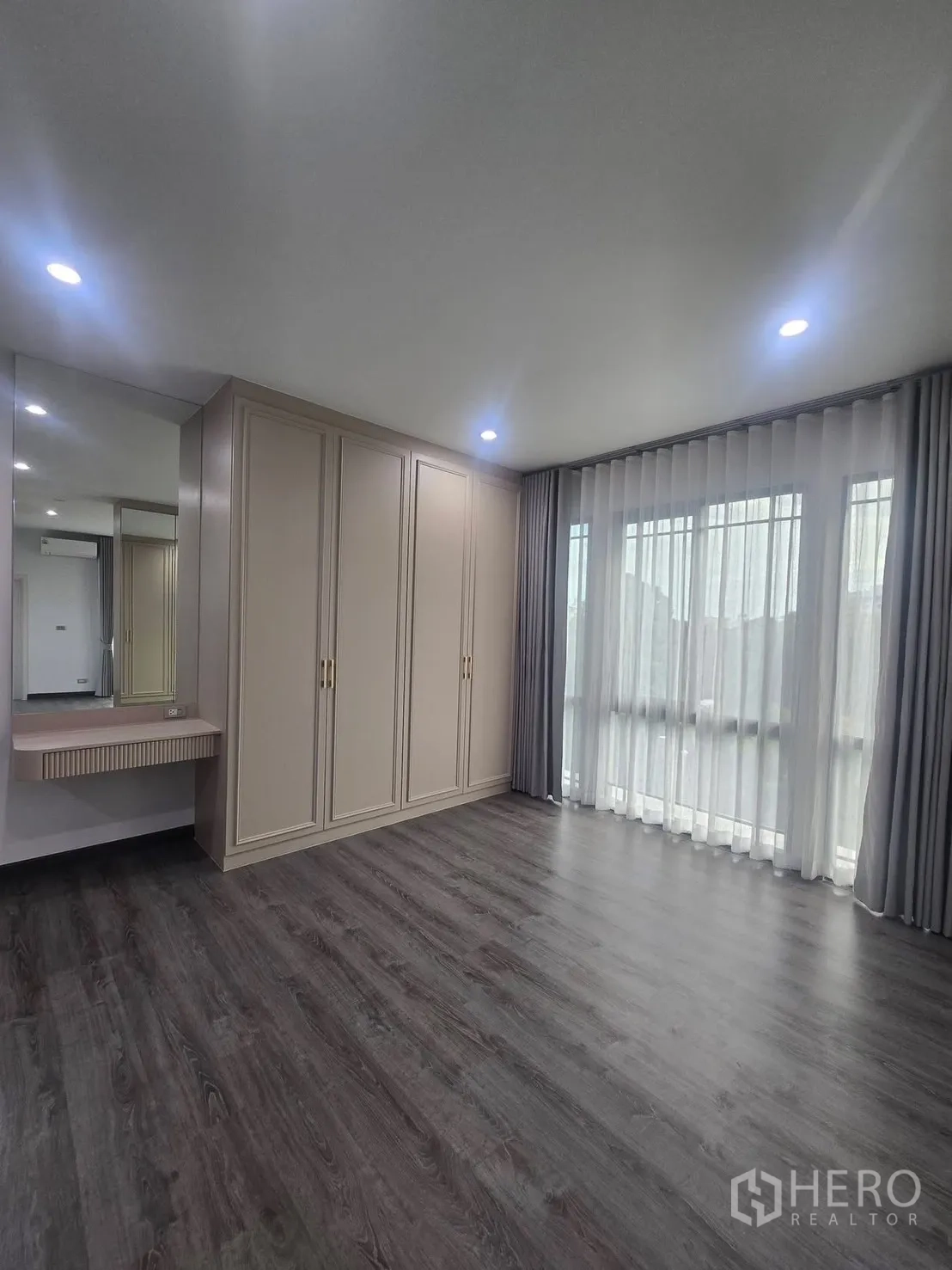 Semi-detached House for rent in Suan Luang, Bangkok - Corner bedroom with built-in wardrobe, dressing table and sheer drapes.