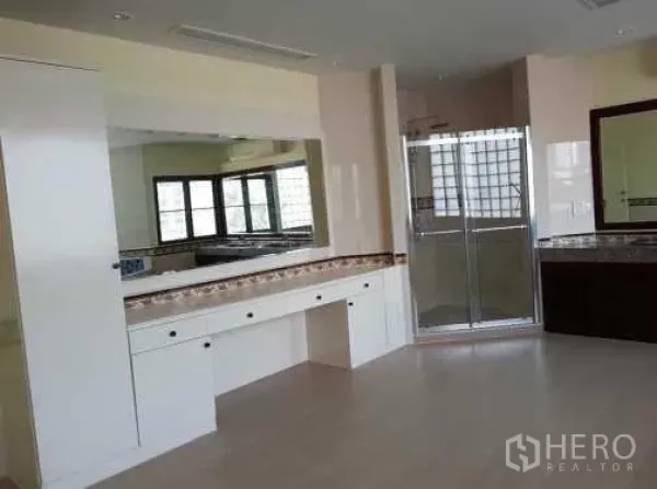 Townhouse for rent in Khlong Toei, Bangkok - Bathroom with large vanity, wide mirror and a glass shower enclosure.