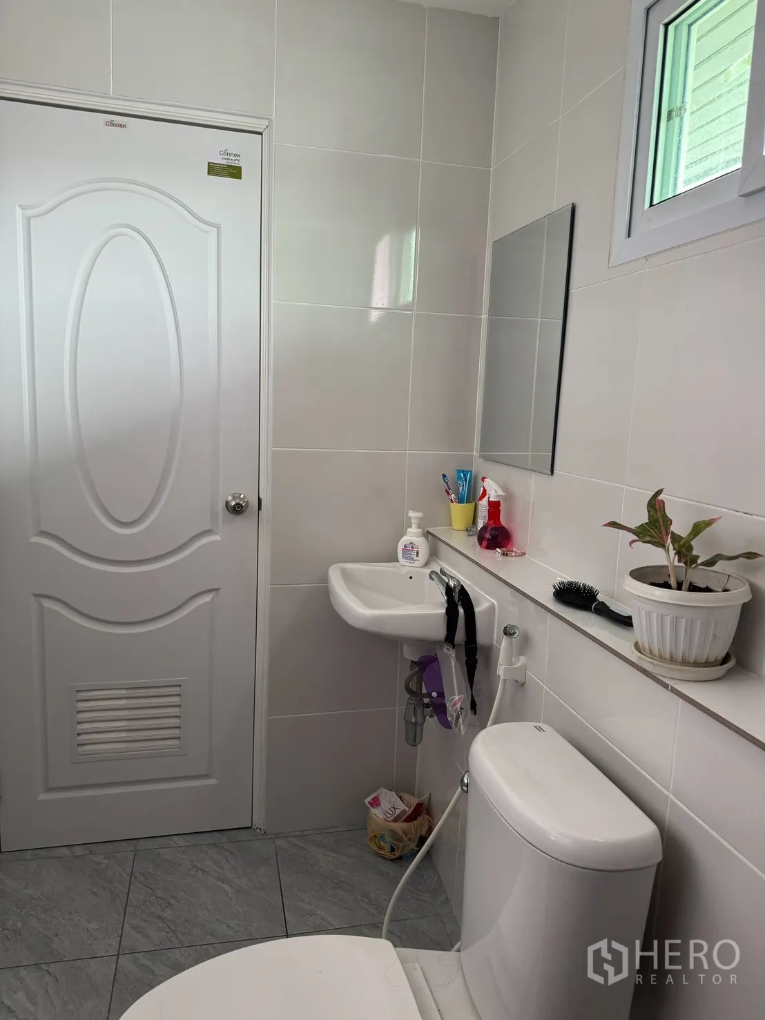 Detached House for rent in Saphan Sung, Bangkok - Bathroom corner with small sink, mirror, window shelf, and toilet.
