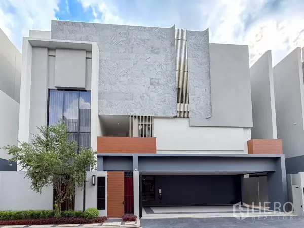 独立式住宅 出租或出售在Bang Kapi, Bangkok - 现代三层独栋住宅立面，石材外墙，宽阔车道与双车位车库。