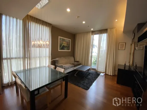 คอนโด ให้เช่าในWatthana, Bangkok - พื้นที่นั่งเล่นและทานอาหารสว่างโปร่ง มีผ้าม่านสูงจรดเพดาน โต๊ะทานอาหารกระจก โซฟา และประตูระเบียง